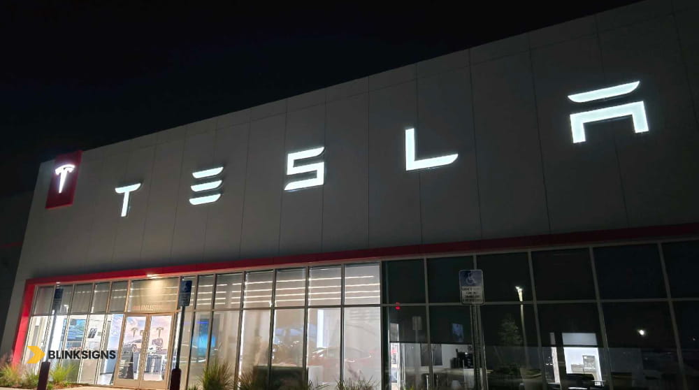 Large white illuminated Tesla LED channel letter building sign mounted against an exterior facade.